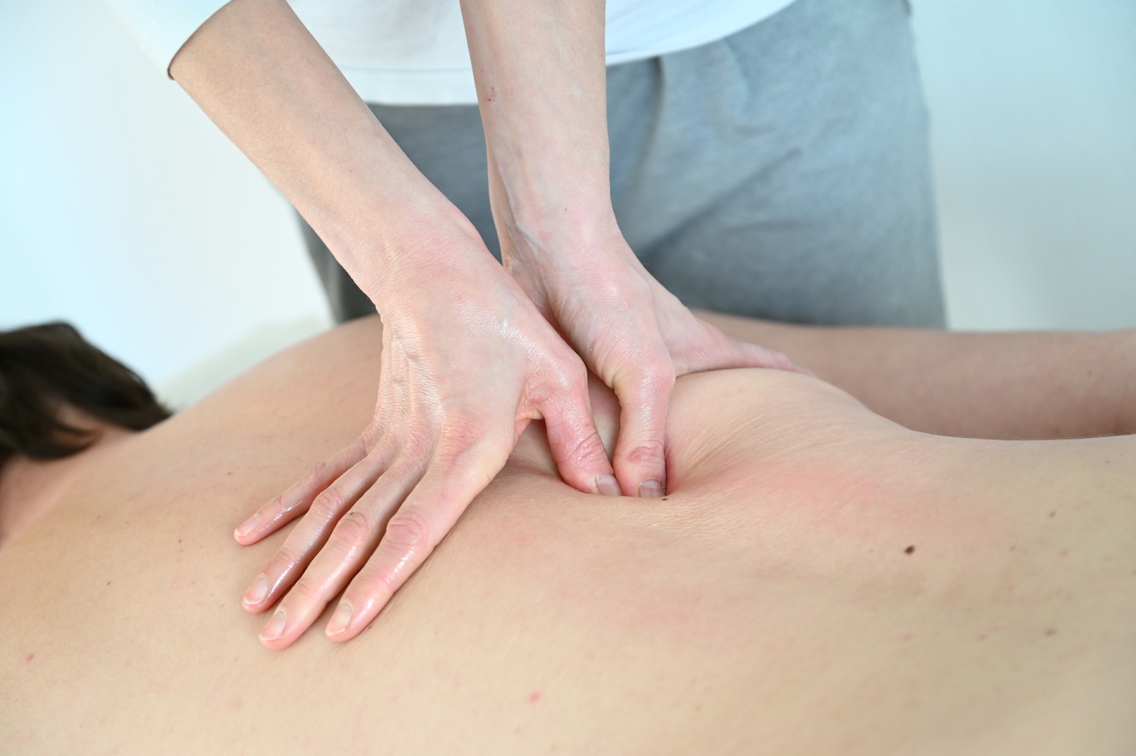 Ein Patient bekommt eine Querfriktion der Rückenstrecker im Rahmen der Manuellen Therapie.