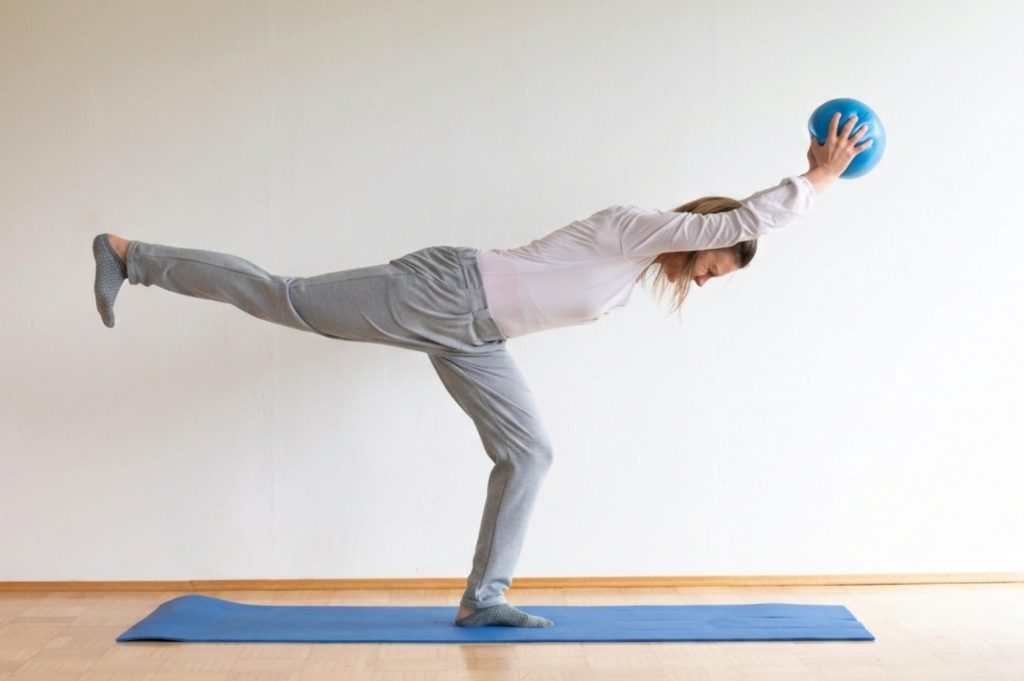 Auf einem Bein stehend, werden Oberkörper, Arme und das freie Bein annährend waagrecht ausgerichtet. Der Redondoball wird mit ausgestreckten Armen gehalten.